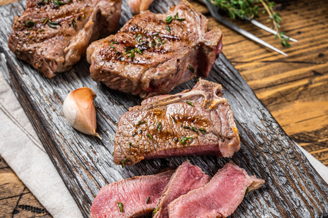 Cooked lamb loin chops on a rustic cutting board