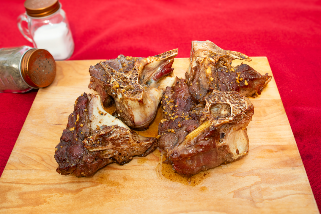 Braised rib chops on a wooden cutting board with a red background